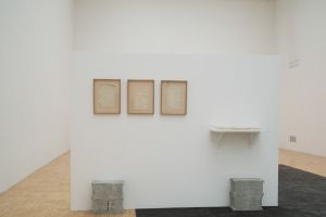 Vue de l’exposition *Toute première fois* à la galerie de l’ESAD de Grenoble, du 8 au 18 décembre 2015. Oscar Tuazon, *169017681742*, 2008 (à gauche). Alghiero E. Boetti, *De bouche à oreille* (à droite). Photo : Renaud Menoud